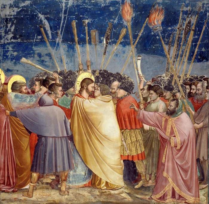 Judas in a yellow cloak embraces Christ amid a crowd carrying torches and spears, against a deep blue sky.
